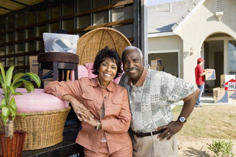 Senior moving services. Two active senior citizens behind a moving truck.