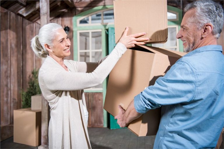Moving services for seniors. Professional mover take a box from a senior citizen.